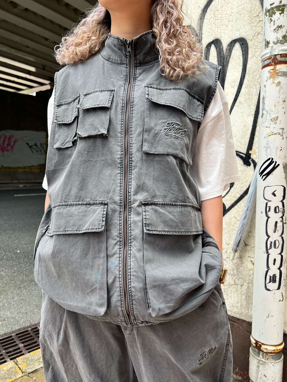 グレー系のベスト、グレー系のカーゴパンツ、ブラック系のニットキャップ/ビーニーを着用したレディースの夏コーディネートの3枚目の写真