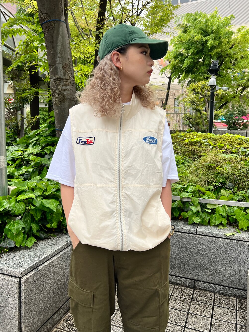 ホワイト系のベスト、グリーン系のカーゴパンツ、ホワイト系のTシャツ/カットソーを着用したレディースの春コーディネートの2枚目の写真