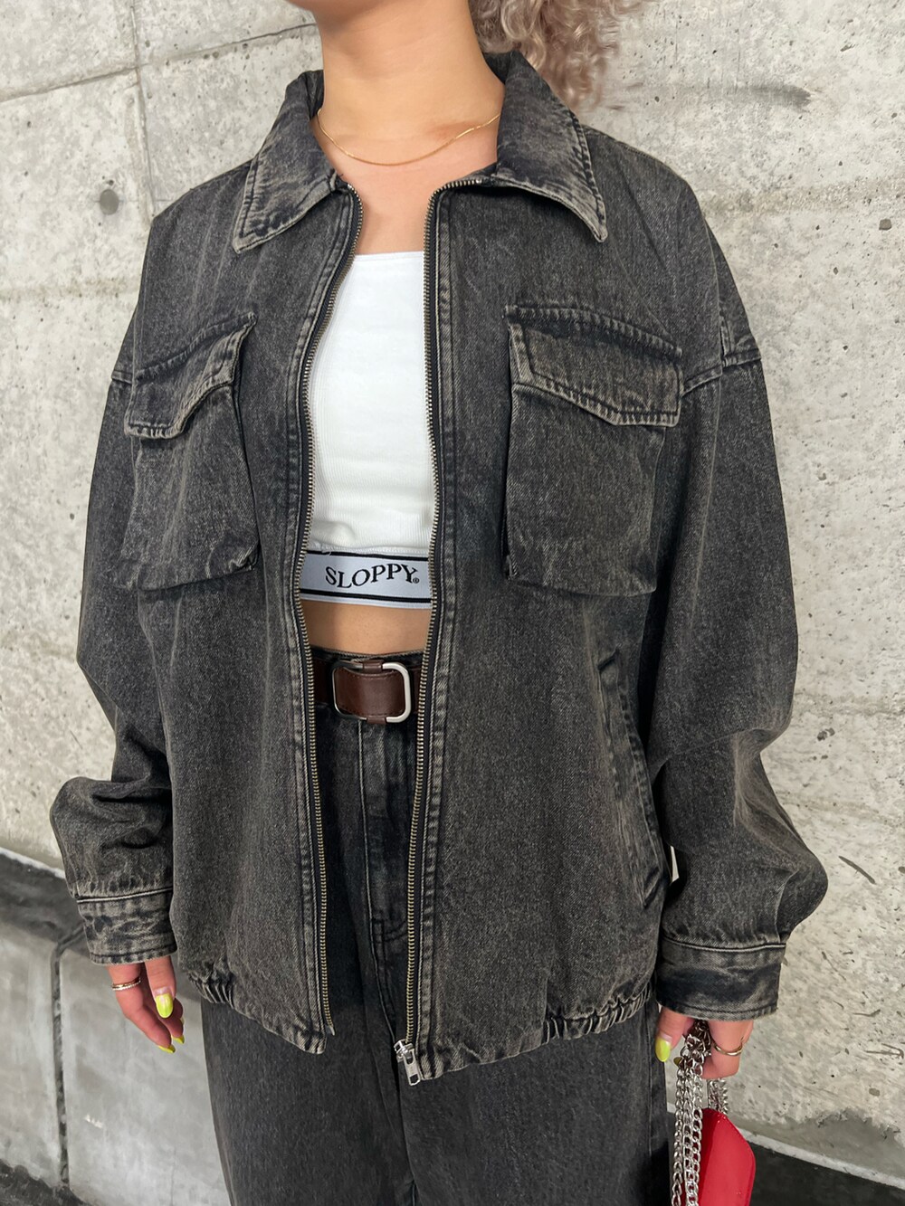 ブラウン系のブルゾン、ホワイト系のキャミソール、ブラウン系のデニムパンツを着用したレディースの秋コーディネートの3枚目の写真