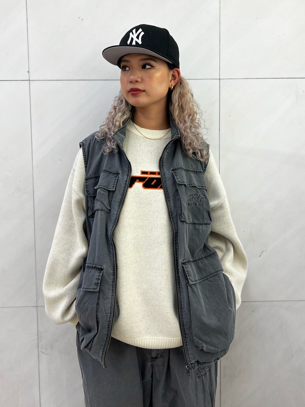 ホワイト系のニット/セーター、グレー系のベスト、グレー系のカーゴパンツを着用したレディースの秋コーディネートの2枚目の写真