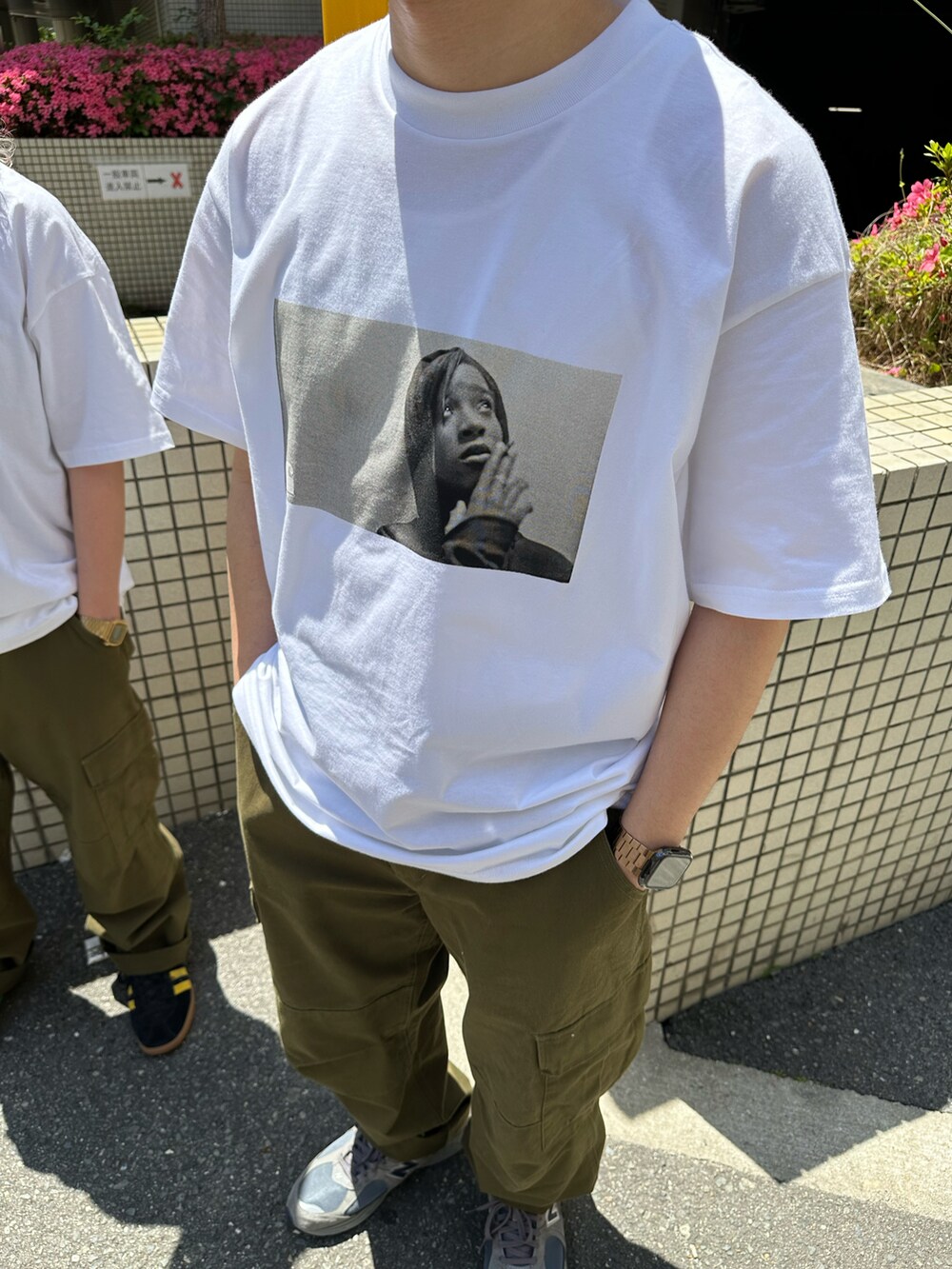 ホワイト系のTシャツ/カットソー、グリーン系のカーゴパンツ、ブラック系のスニーカーを着用したレディースの春コーディネートの4枚目の写真