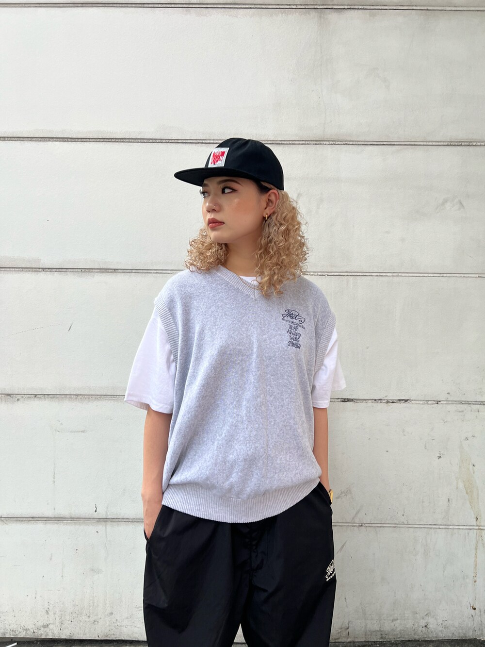 グレー系のベスト、ホワイト系のTシャツ/カットソー、ブラック系のカーゴパンツを着用したレディースの春コーディネートの3枚目の写真