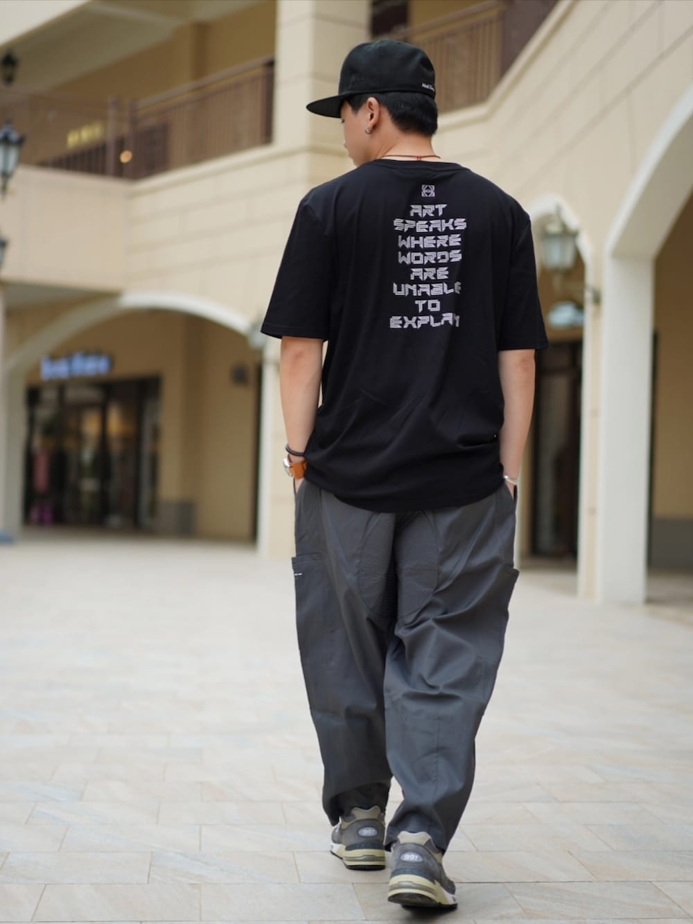 グレー系のチノパンツ、グレー系のシューズ、ブラック系のキャップを着用したメンズの春コーディネートの3枚目の写真