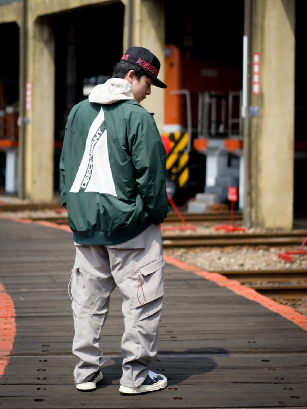 グリーン系のトレンチコート、グレー系のチノパンツ、グレー系のスニーカーを着用したメンズの春コーディネートの2枚目の写真