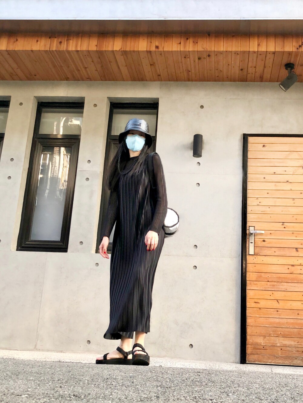 ブラック系のトップス、ブラック系のジャンパースカート、シルバー系のバッグを着用したレディースの秋コーディネートの4枚目の写真