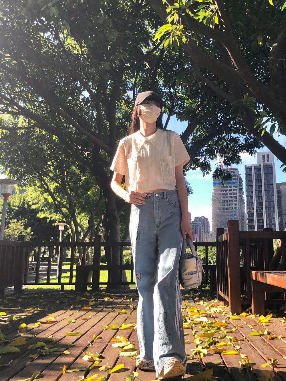 ベージュ系のシャツ/ブラウス、ブルー系のデニムパンツ、シルバー系のバッグを着用したレディースの夏コーディネートの2枚目の写真