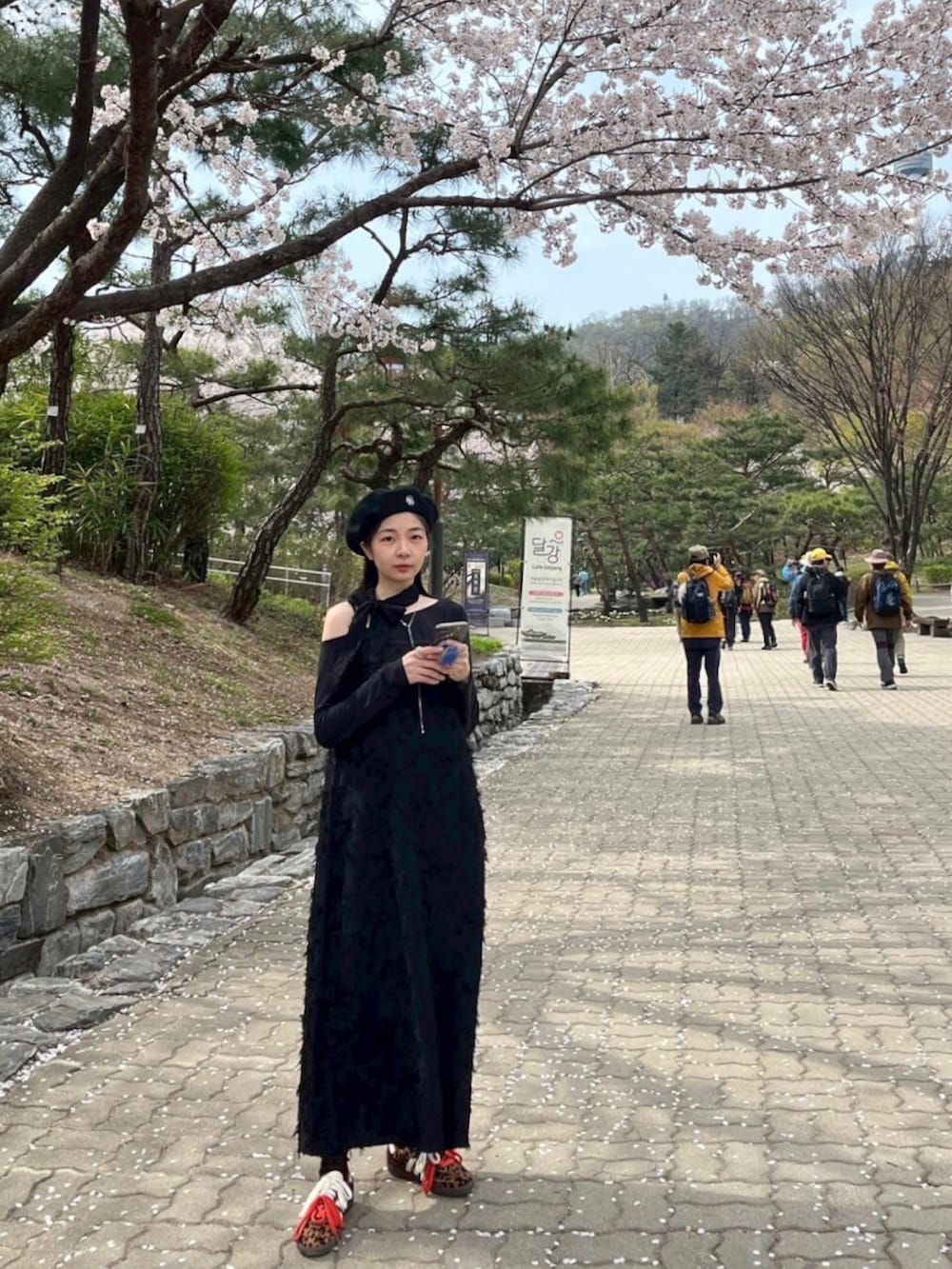 ブラック系のスーツジャケット、ブラック系のジャンパースカート、ブラック系のトップスを着用したレディースの春コーディネートの4枚目の写真