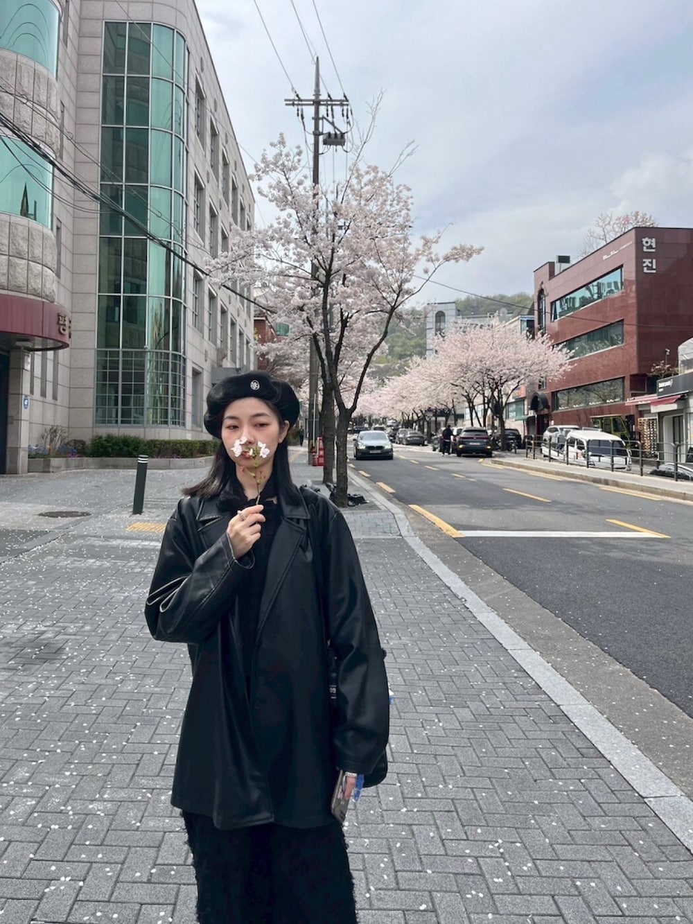 ブラック系のスーツジャケット、ブラック系のジャンパースカート、ブラック系のトップスを着用したレディースの春コーディネートの2枚目の写真