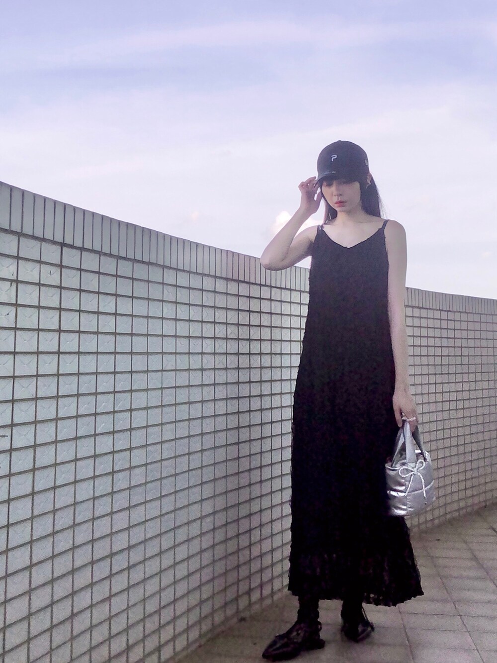 ホワイト系のスニーカー、ブラック系のジャンパースカート、シルバー系のバッグを着用したレディースの夏コーディネートの4枚目の写真