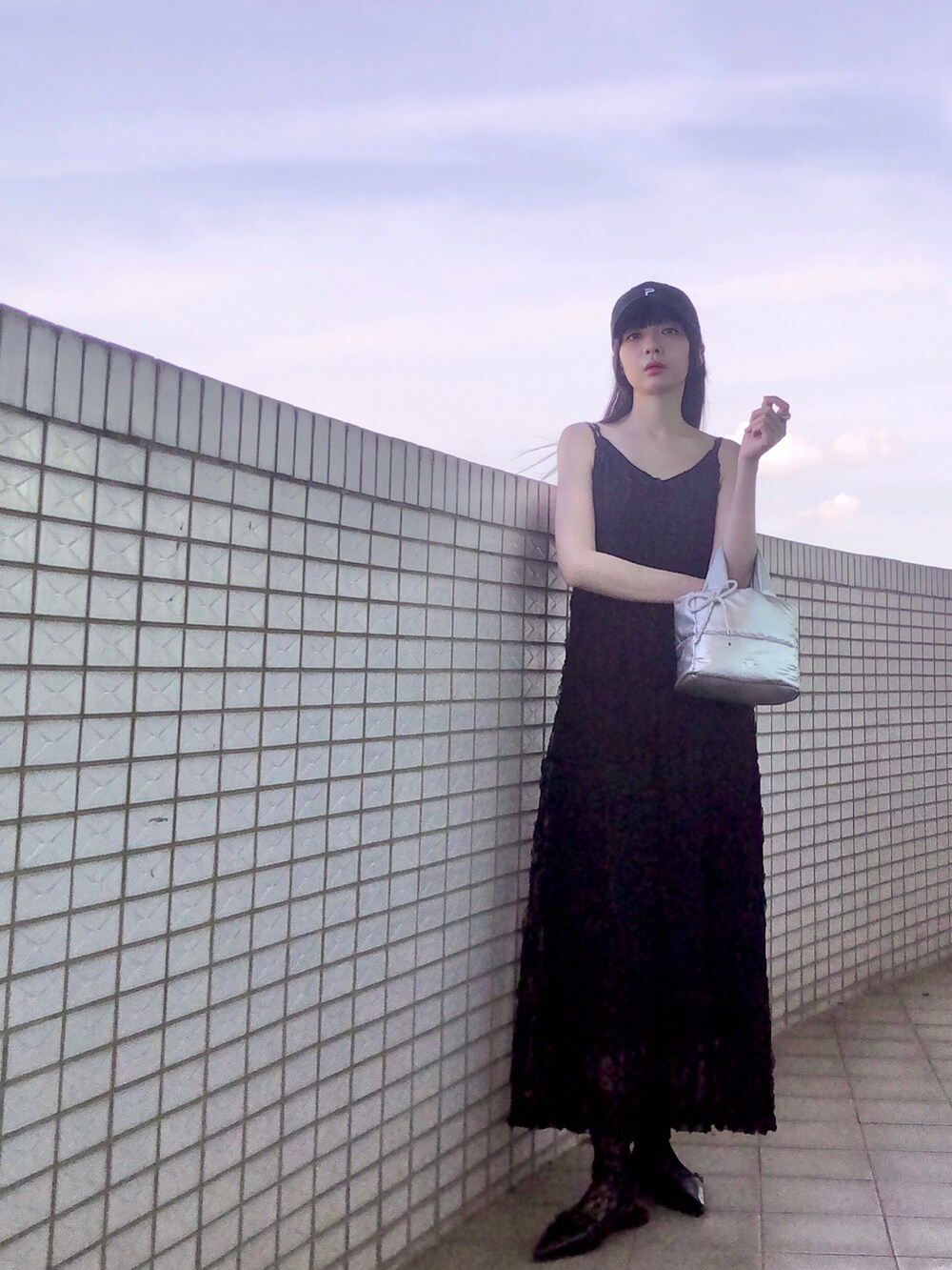 ホワイト系のスニーカー、ブラック系のジャンパースカート、シルバー系のバッグを着用したレディースの夏コーディネートの5枚目の写真