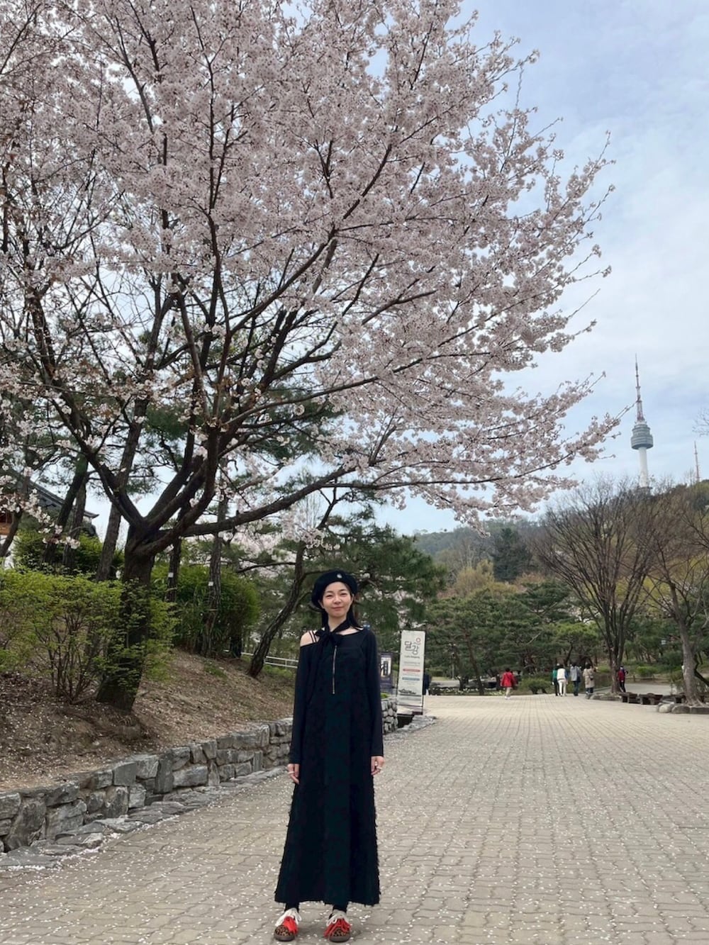 ブラック系のスーツジャケット、ブラック系のジャンパースカート、ブラック系のトップスを着用したレディースの春コーディネートの5枚目の写真