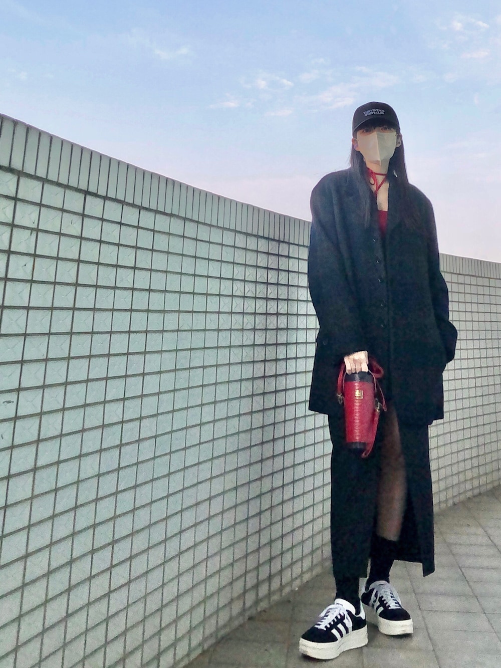 ブラック系のスニーカー、レッド系のトップス、ブルー系のムートンコートを着用したレディースの春コーディネートの3枚目の写真