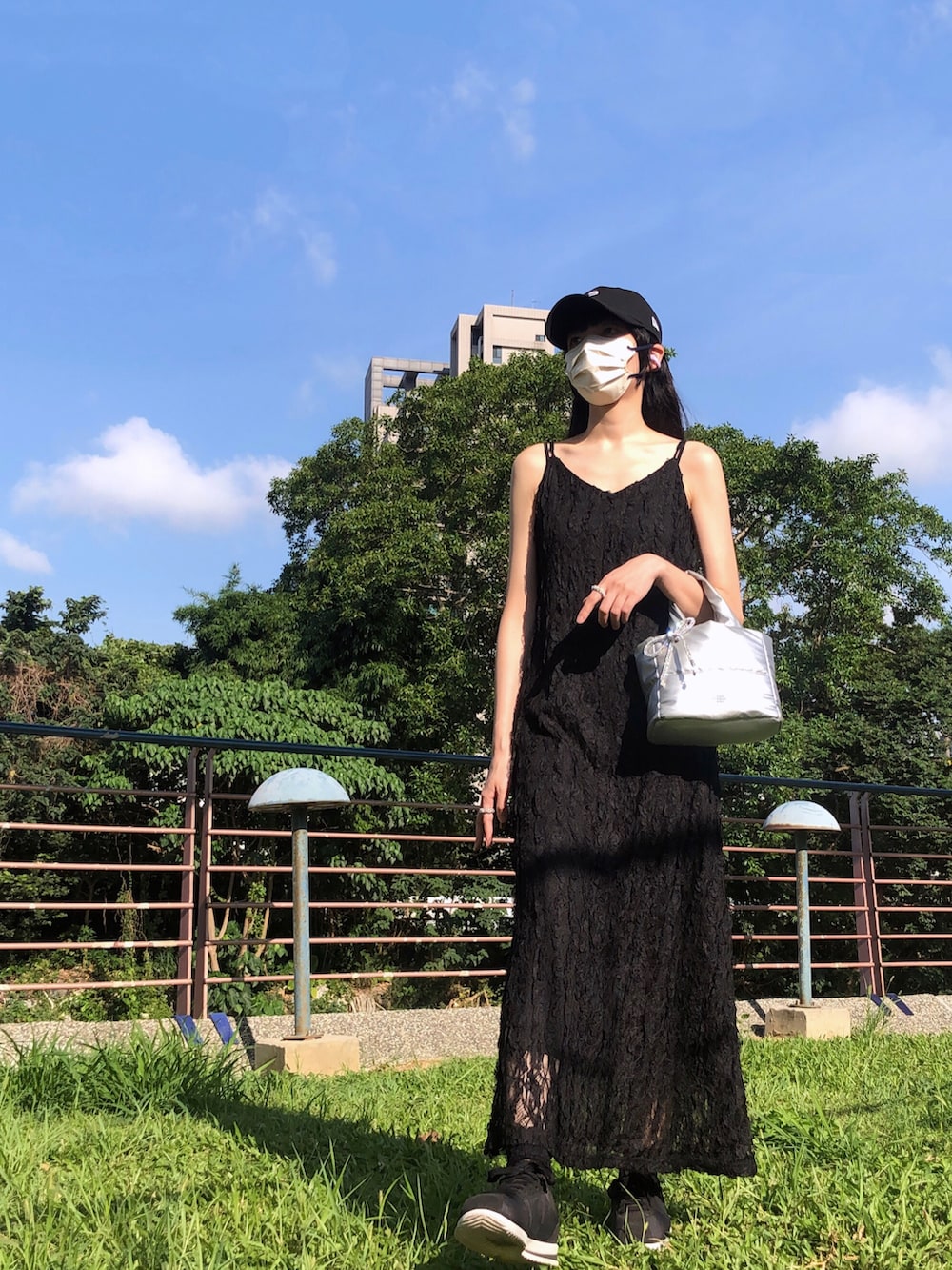 ホワイト系のスニーカー、ブラック系のジャンパースカート、シルバー系のバッグを着用したレディースの夏コーディネートの3枚目の写真