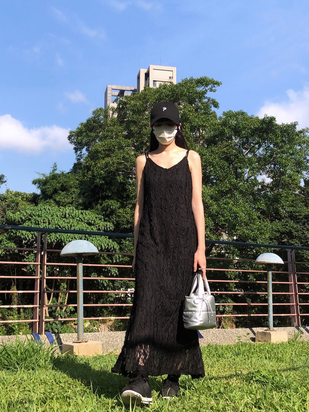 ホワイト系のスニーカー、ブラック系のジャンパースカート、シルバー系のバッグを着用したレディースの夏コーディネートの2枚目の写真