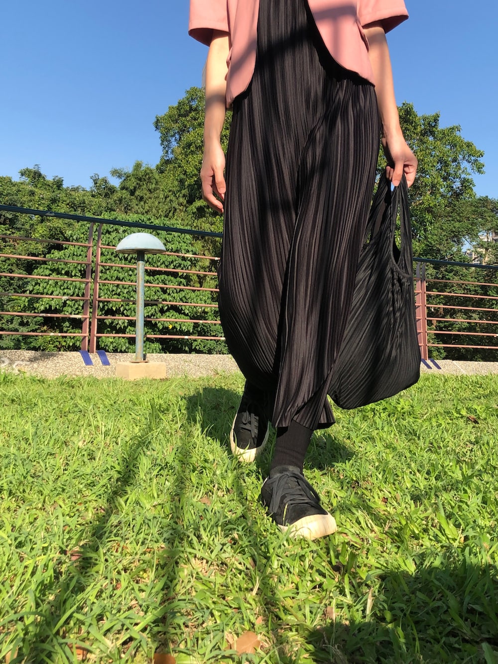 ブラック系のスニーカー、ブラック系のジャンパースカート、ピンク系のスーツジャケットを着用したレディースの秋コーディネートの2枚目の写真