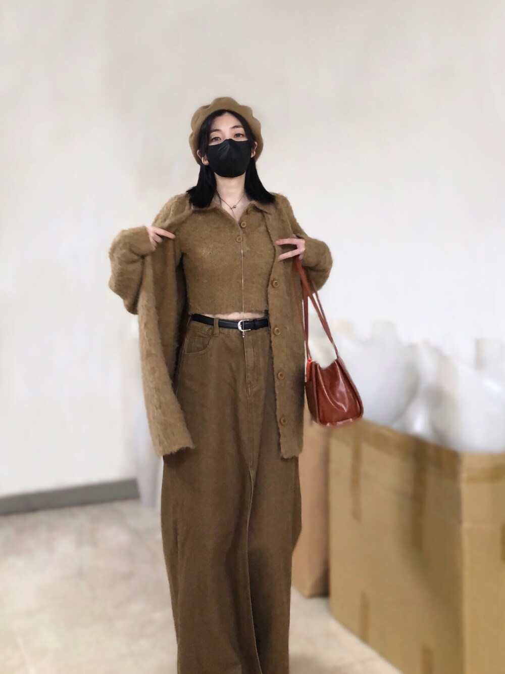 ブラウン系のニット/セーター、ブラウン系のデニムスカート、その他のショルダーバッグを着用したレディースの春コーディネートの3枚目の写真