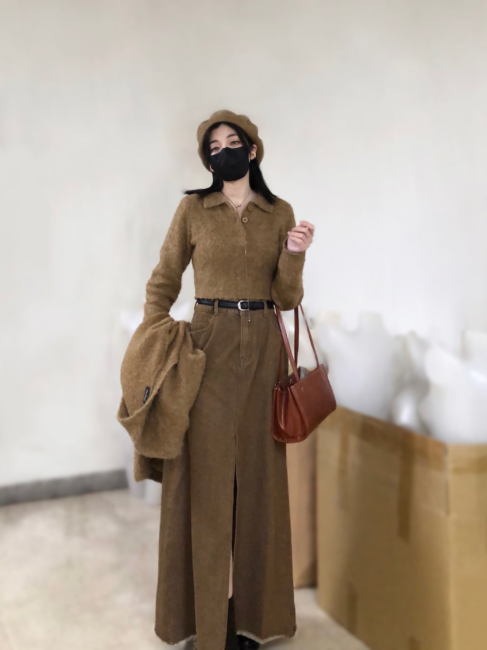 ブラウン系のニット/セーター、ブラウン系のデニムスカート、その他のショルダーバッグを着用したレディースの春コーディネートの2枚目の写真