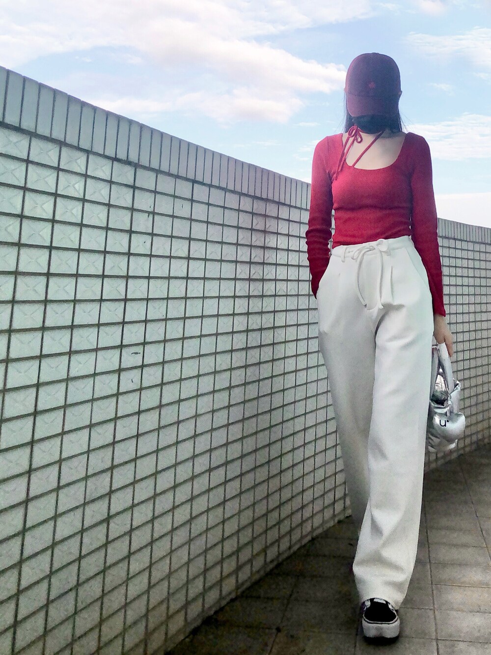 レッド系のトップス、ホワイト系のスラックス、シルバー系のバッグを着用したレディースの冬コーディネートの3枚目の写真