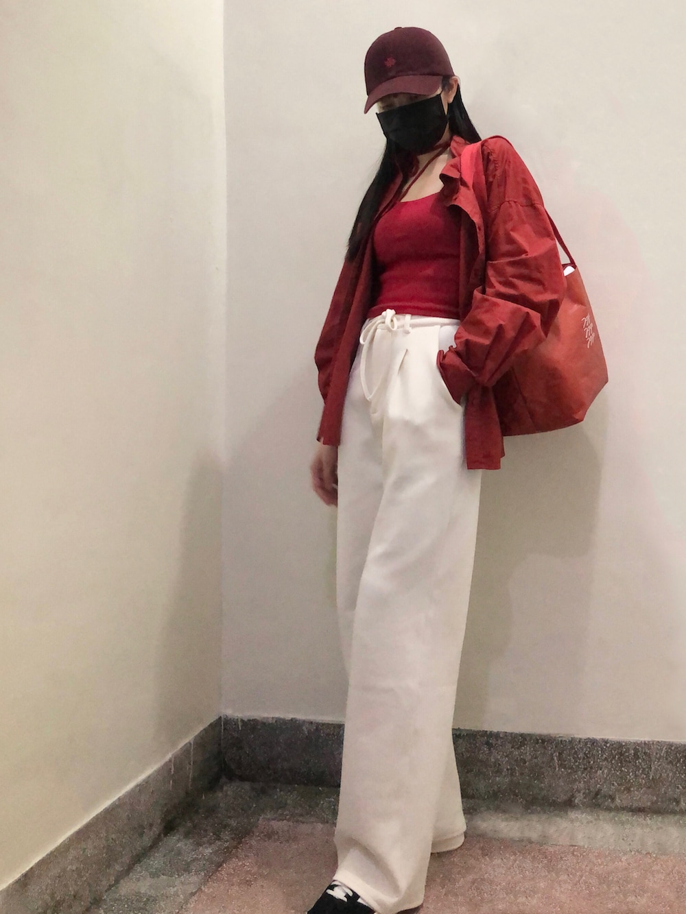 レッド系のトップス、ホワイト系のスラックス、シルバー系のバッグを着用したレディースの冬コーディネートの2枚目の写真