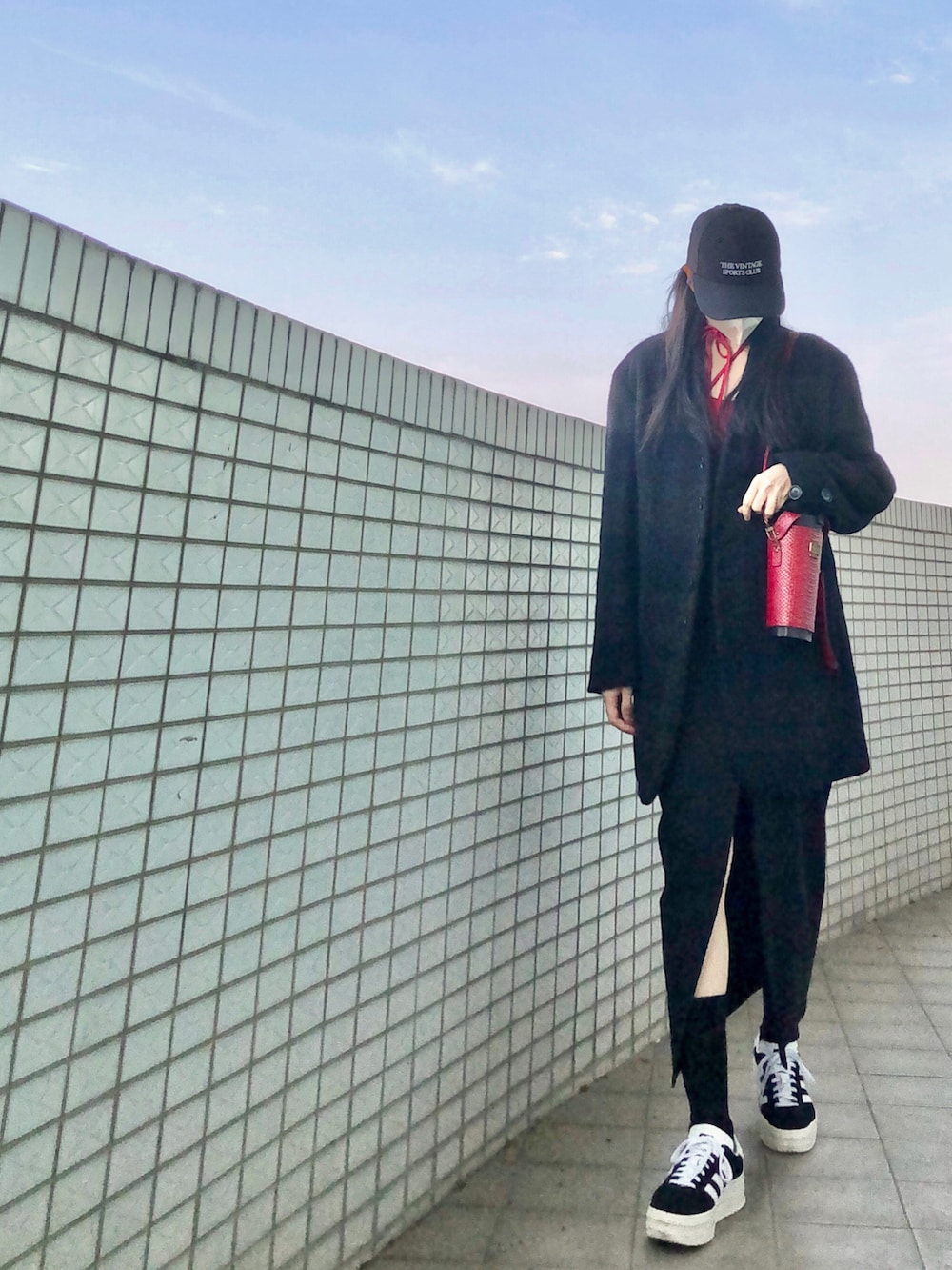 ブラック系のスニーカー、レッド系のトップス、ブルー系のムートンコートを着用したレディースの春コーディネートの2枚目の写真