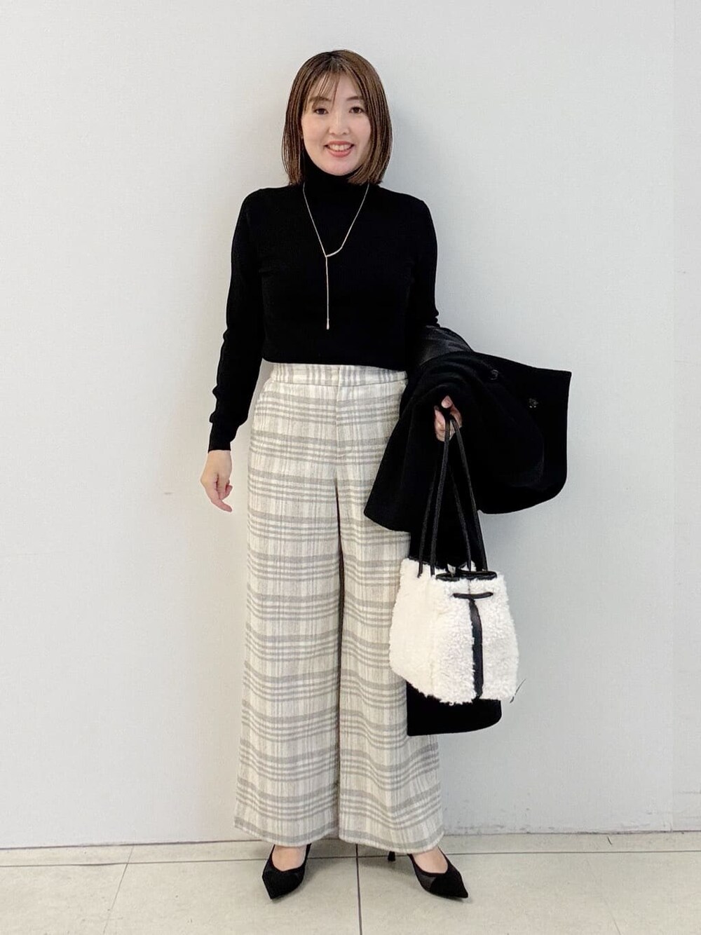 ブラック系のニット/セーター、グレー系のその他パンツ、ホワイト系のショルダーバッグを着用したレディースの冬コーディネートの5枚目の写真