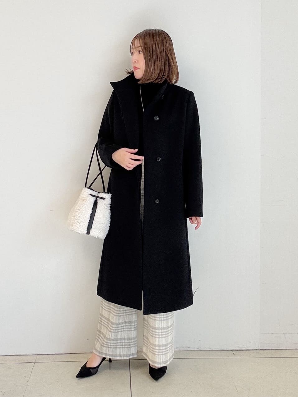 ブラック系のニット/セーター、グレー系のその他パンツ、ホワイト系のショルダーバッグを着用したレディースの冬コーディネートの3枚目の写真