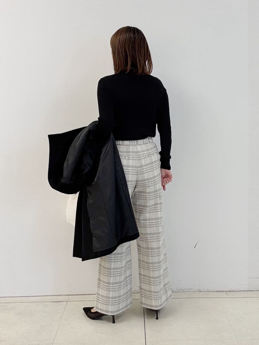 ブラック系のニット/セーター、グレー系のその他パンツ、ホワイト系のショルダーバッグを着用したレディースの冬コーディネートの4枚目の写真