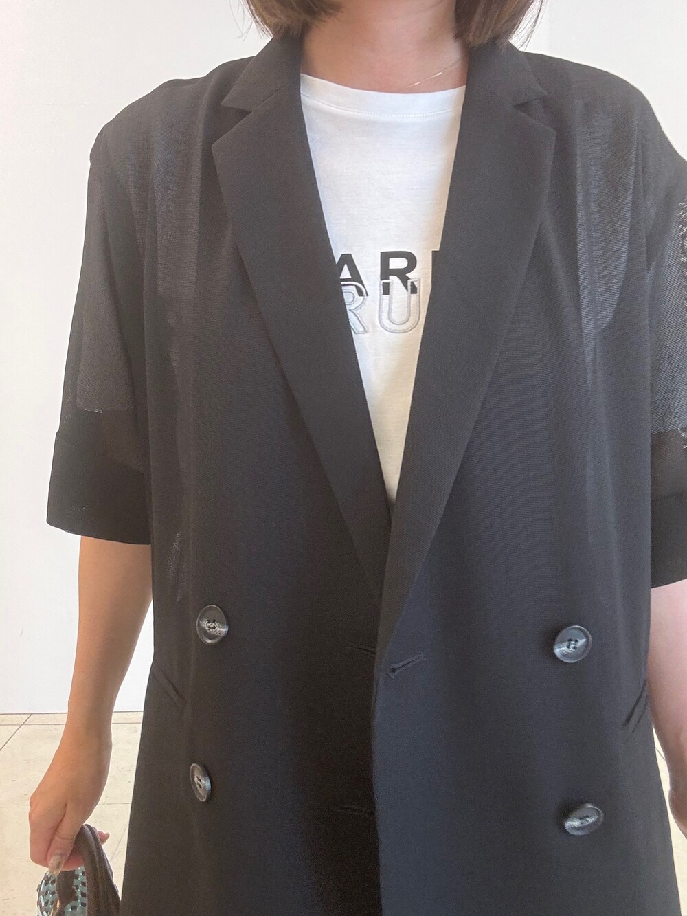 ホワイト系のTシャツ/カットソー、ブラック系のパンプス、ブラック系のテーラードジャケットを着用したレディースの春コーディネートの6枚目の写真