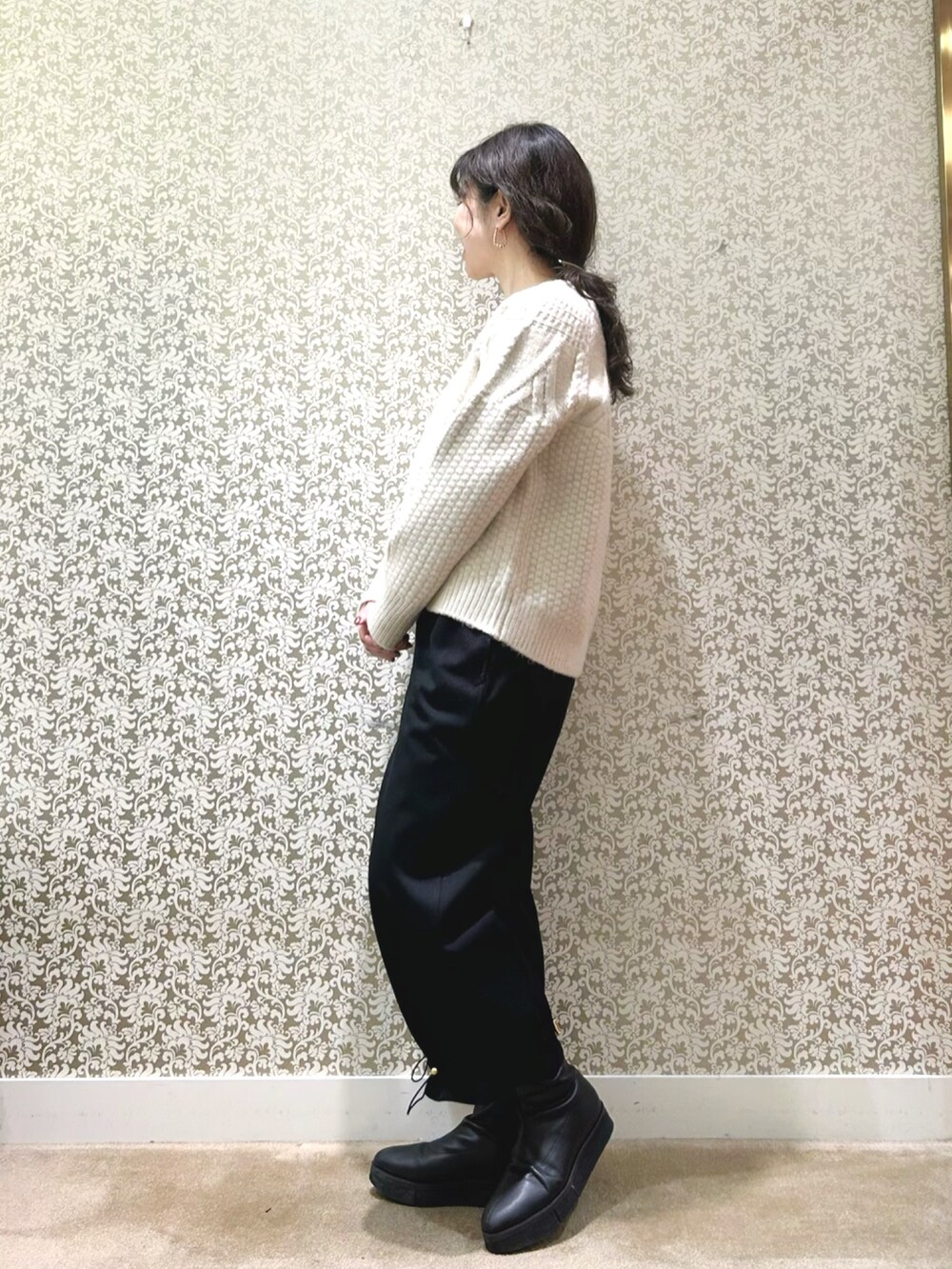 ブラック系のノーカラーコート、ベージュ系のニット/セーター、ブラック系のその他パンツを着用したレディースの冬コーディネートの5枚目の写真