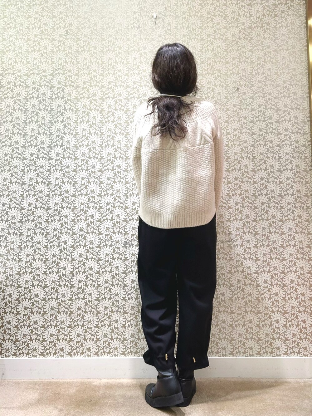 ブラック系のノーカラーコート、ベージュ系のニット/セーター、ブラック系のその他パンツを着用したレディースの冬コーディネートの6枚目の写真