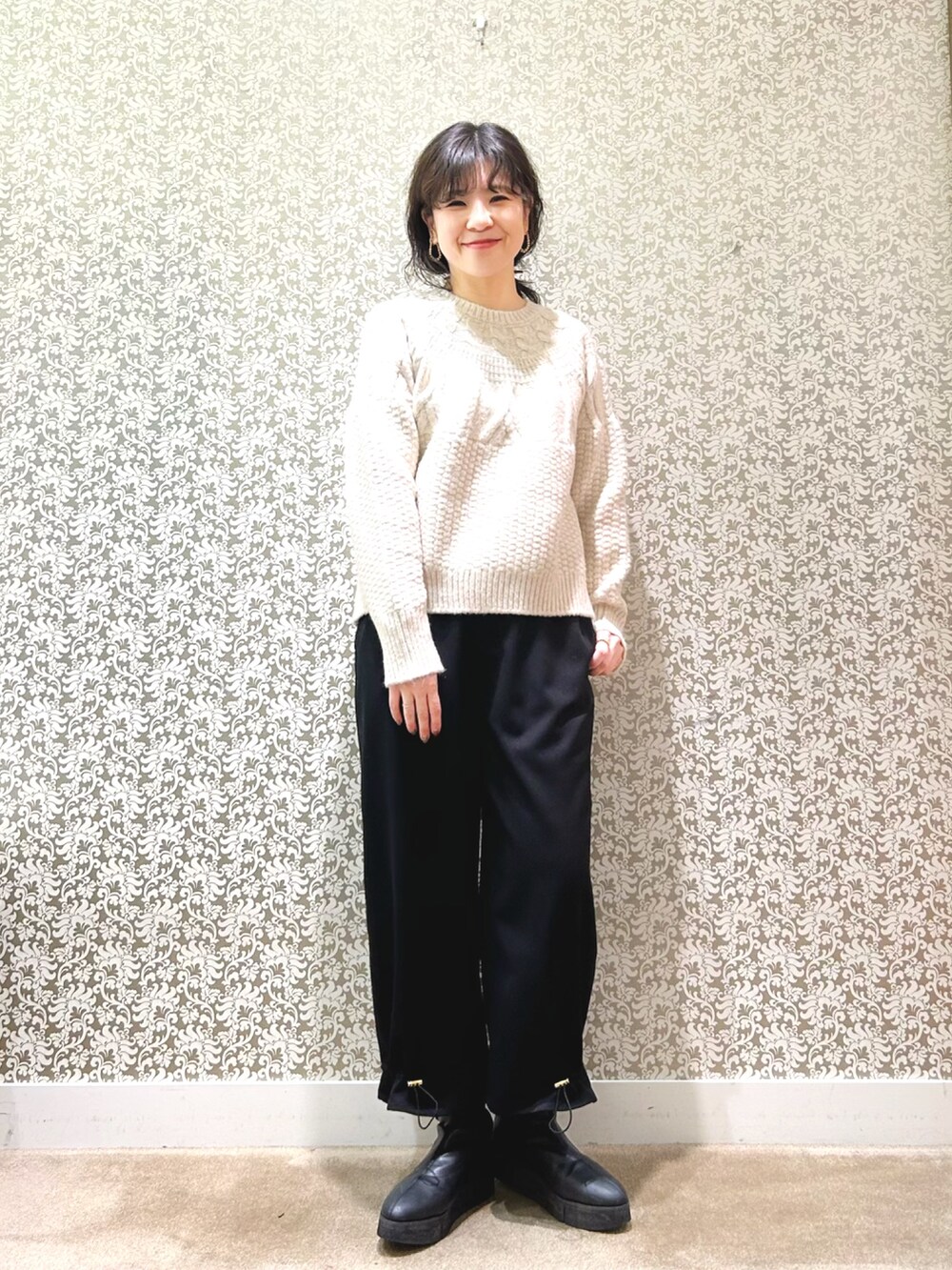 ブラック系のノーカラーコート、ベージュ系のニット/セーター、ブラック系のその他パンツを着用したレディースの冬コーディネートの4枚目の写真