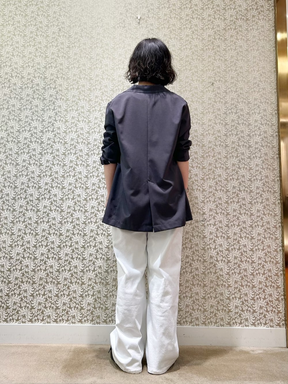 グレー系のテーラードジャケット、ブラック系のタンクトップ、ホワイト系のデニムパンツを着用したレディースの春コーディネートの3枚目の写真