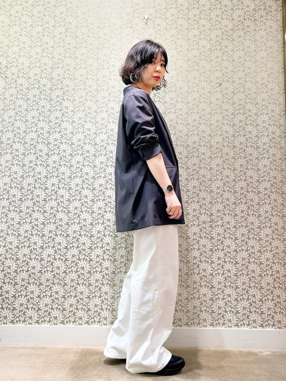 グレー系のテーラードジャケット、ブラック系のタンクトップ、ホワイト系のデニムパンツを着用したレディースの春コーディネートの2枚目の写真