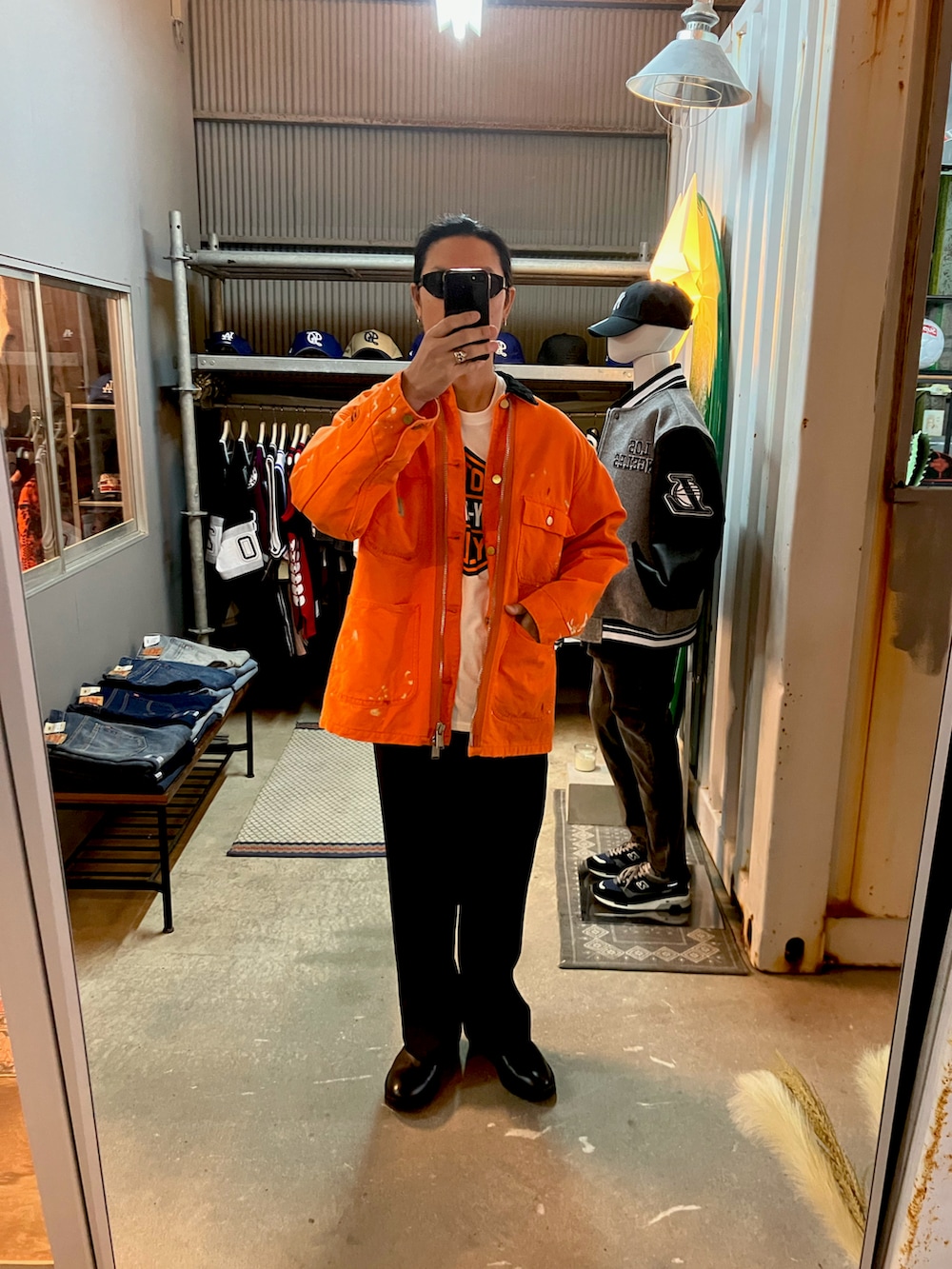 オレンジ系のカバーオール、ブラック系のスラックス、ブラック系のブーツを着用したメンズの冬コーディネートの2枚目の写真