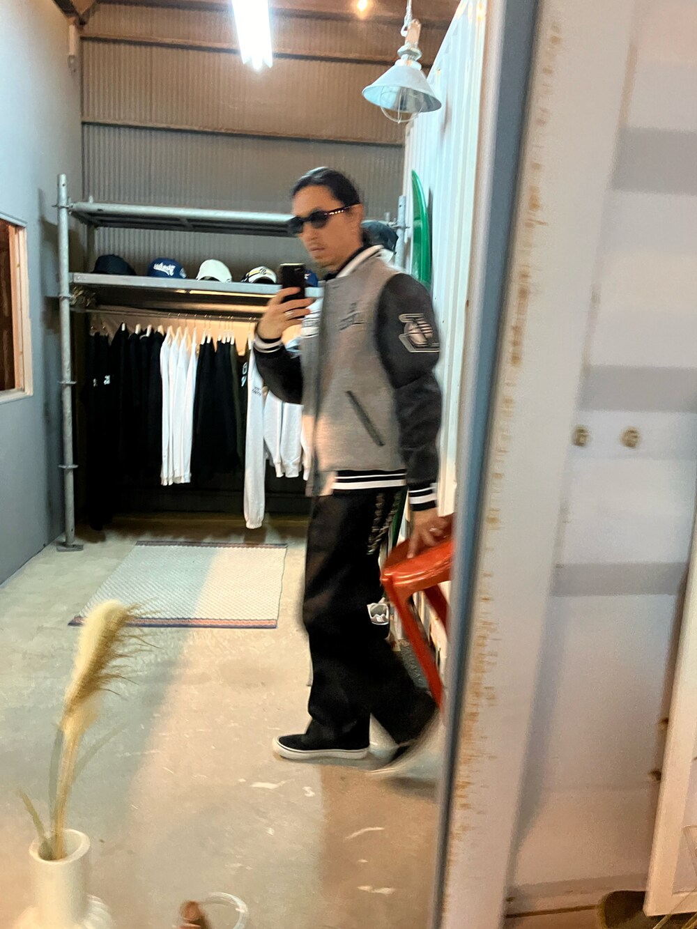 グレー系のスタジャン、ブラック系のスラックス、ブラック系のスニーカーを着用したメンズの秋コーディネートの4枚目の写真