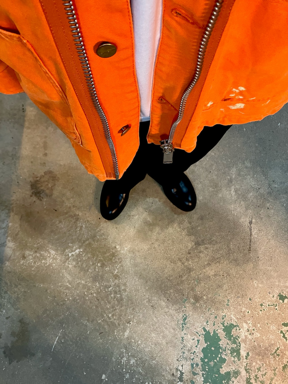 オレンジ系のカバーオール、ブラック系のスラックス、ブラック系のブーツを着用したメンズの冬コーディネートの4枚目の写真