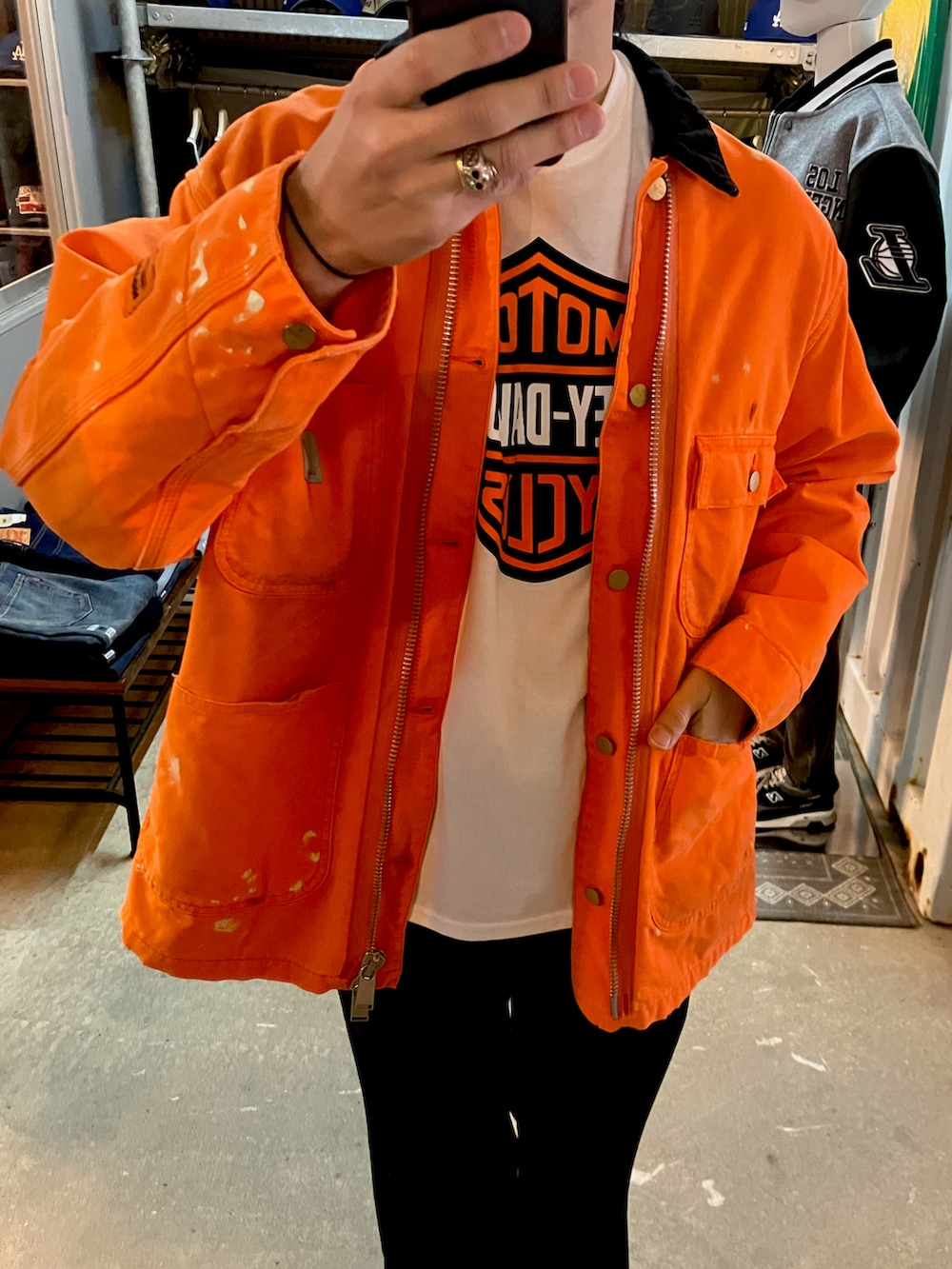 オレンジ系のカバーオール、ブラック系のスラックス、ブラック系のブーツを着用したメンズの冬コーディネートの3枚目の写真