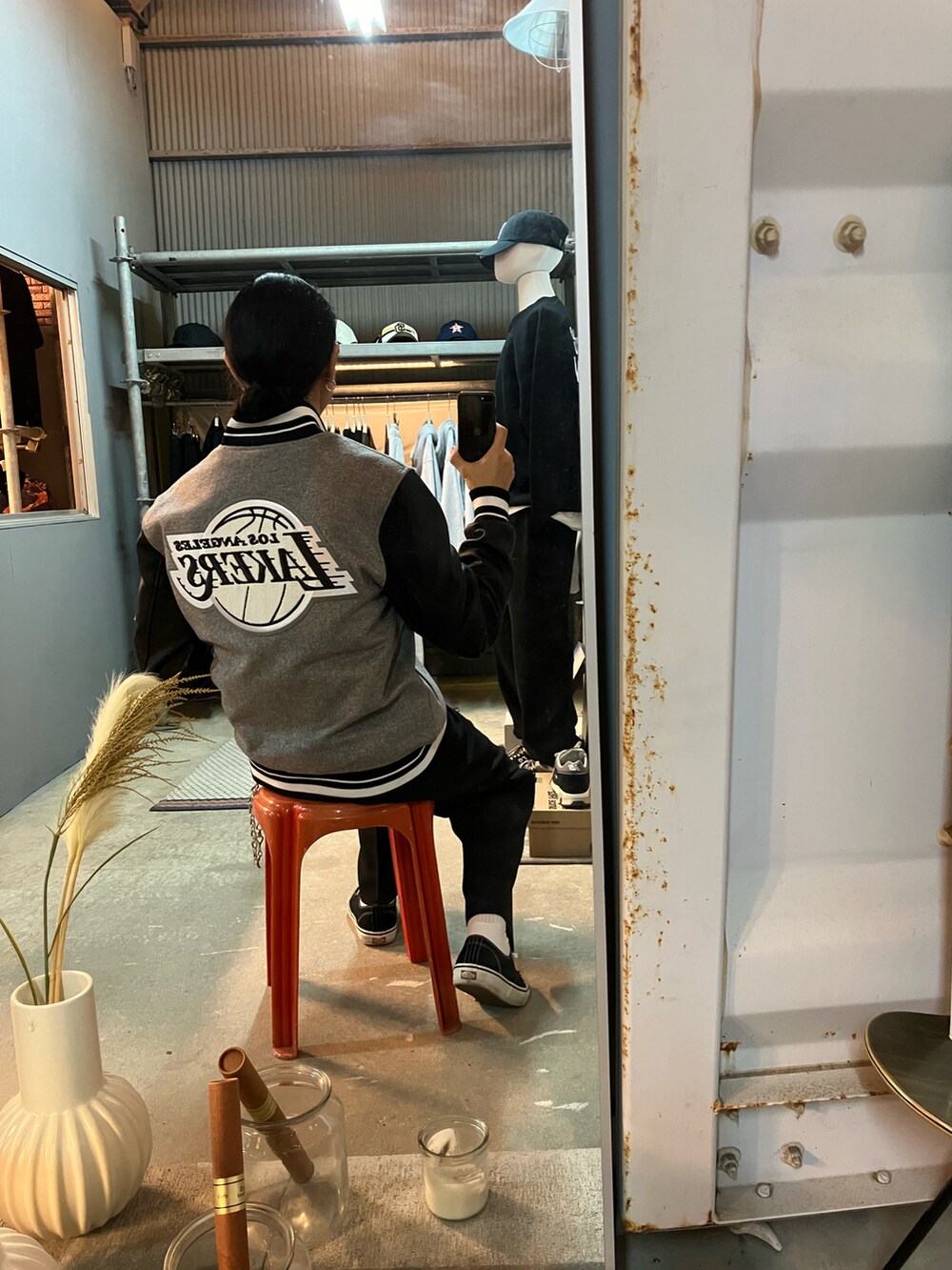 グレー系のスタジャン、ブラック系のスラックス、ブラック系のスニーカーを着用したメンズの秋コーディネートの3枚目の写真