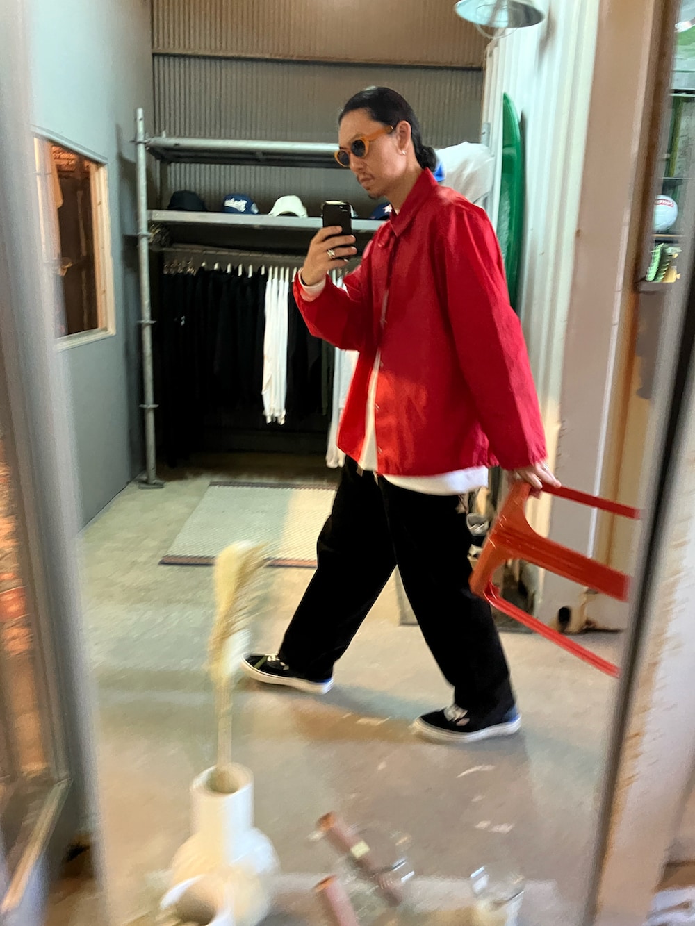 レッド系のナイロンジャケット、ブラウン系のその他パンツ、ブラック系のスニーカーを着用したメンズの秋コーディネートの2枚目の写真