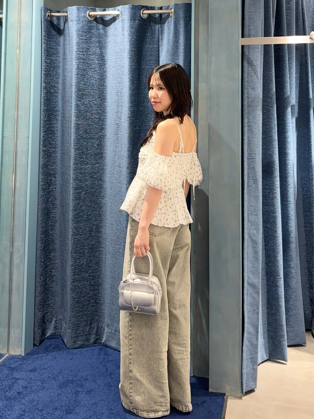 ホワイト系のシャツ/ブラウス、ブルー系のデニムパンツ、シルバー系のボストンバッグを着用したレディースの春コーディネートの2枚目の写真