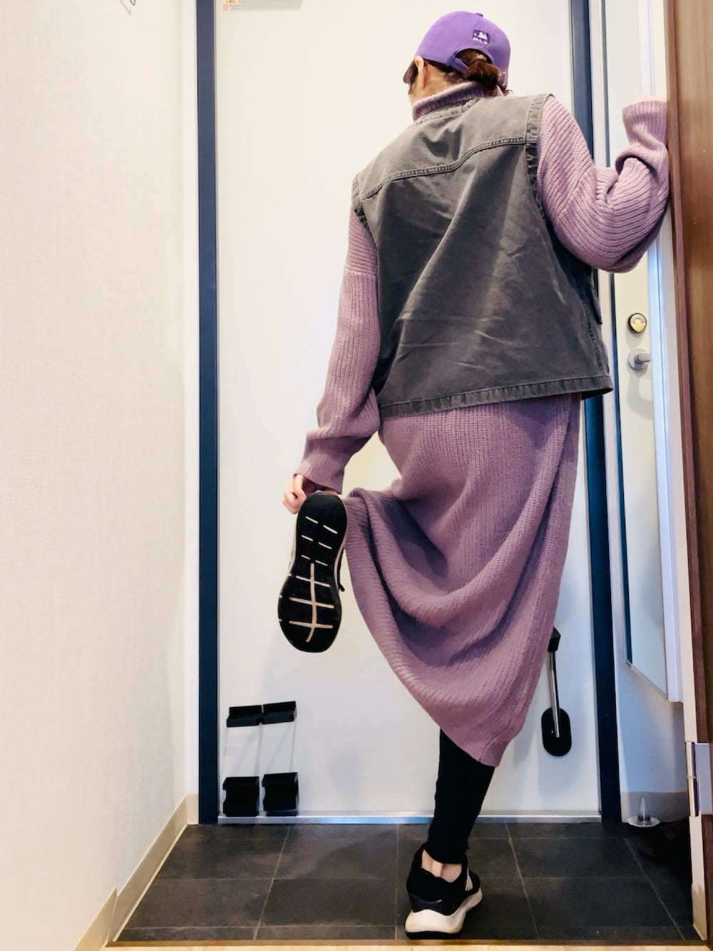 パープル系のワンピース、ブラック系のベスト、ブラック系のスニーカーを着用したレディースの秋コーディネートの3枚目の写真