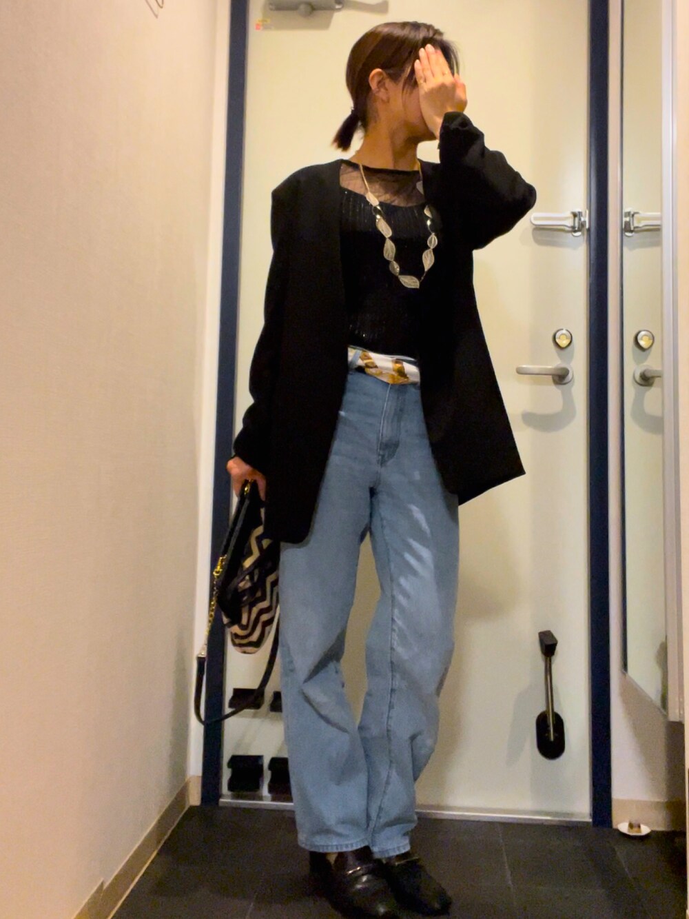 ブルー系のデニムパンツ、ブラック系のパンプス、その他のクラッチバッグを着用したレディースの秋コーディネートの2枚目の写真