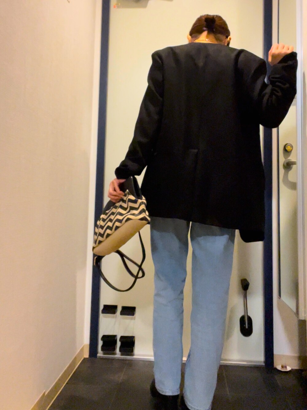 ブルー系のデニムパンツ、ブラック系のパンプス、その他のクラッチバッグを着用したレディースの秋コーディネートの3枚目の写真