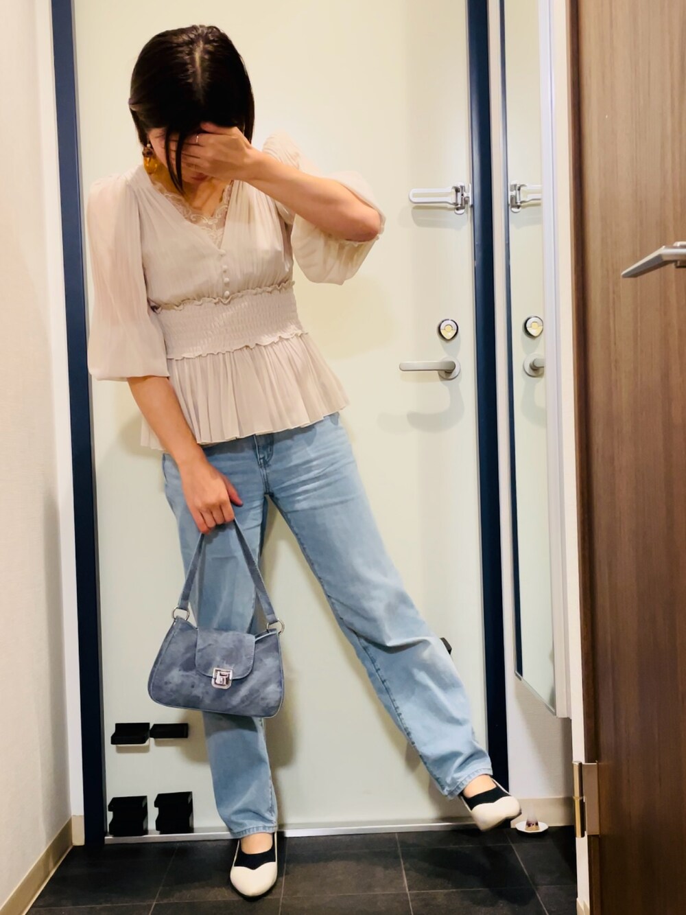 ベージュ系のシャツ/ブラウス、ブルー系のデニムパンツ、ブルー系のハンドバッグを着用したレディースの秋コーディネートの2枚目の写真
