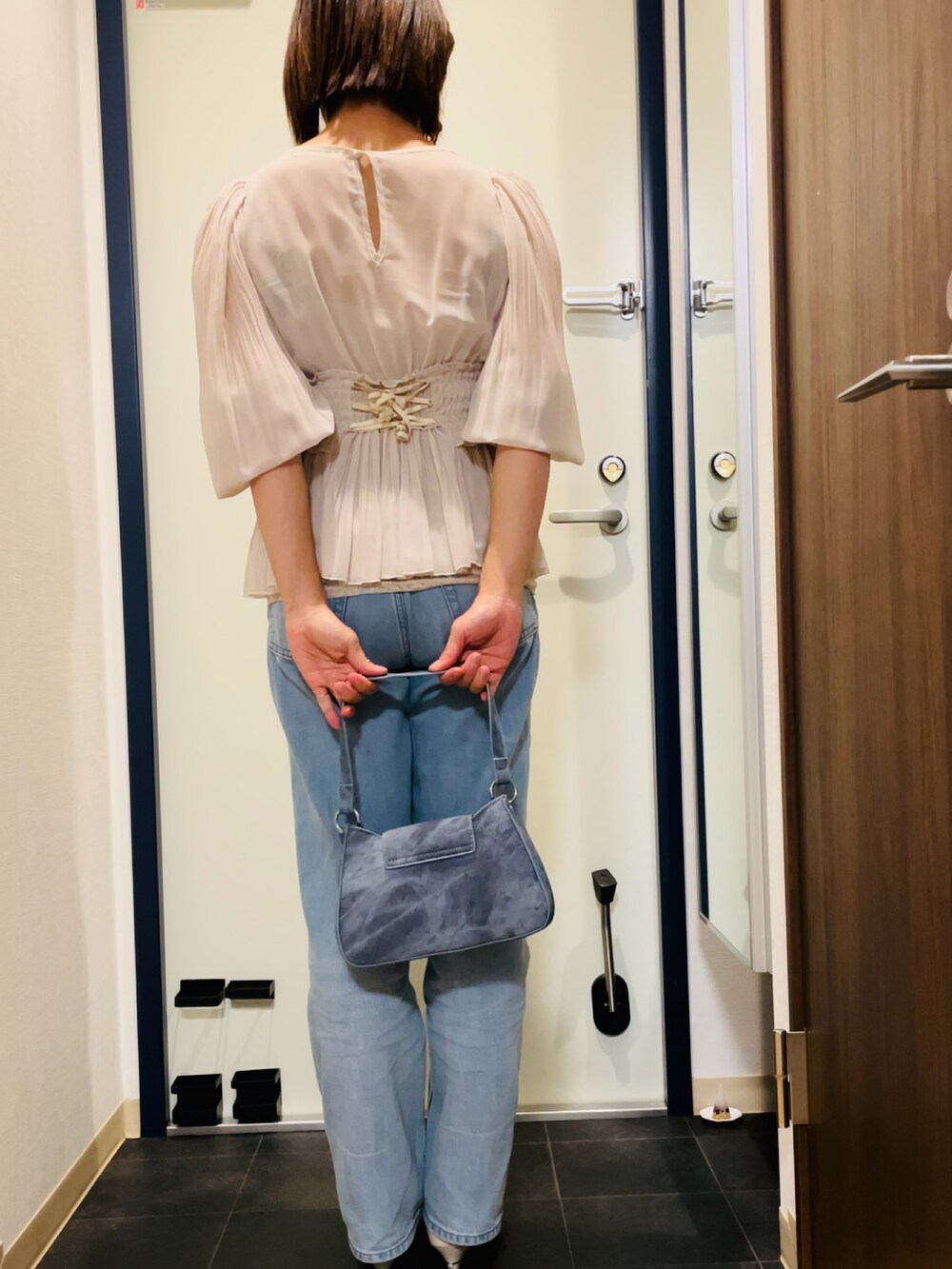 ベージュ系のシャツ/ブラウス、ブルー系のデニムパンツ、ブルー系のハンドバッグを着用したレディースの秋コーディネートの3枚目の写真
