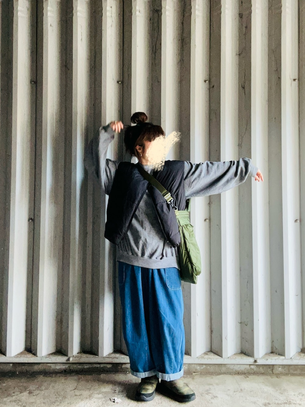 ブラック系のダウンベスト、グレー系のスウェット、ブルー系のデニムパンツを着用したレディースの春コーディネートの2枚目の写真