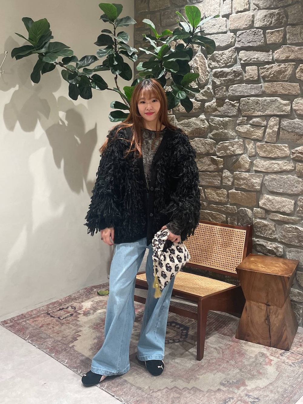 ホワイト系のハンドバッグ、ブルー系のデニムパンツ、ブラック系のカーディガン/ボレロを着用したレディースの冬コーディネートの2枚目の写真