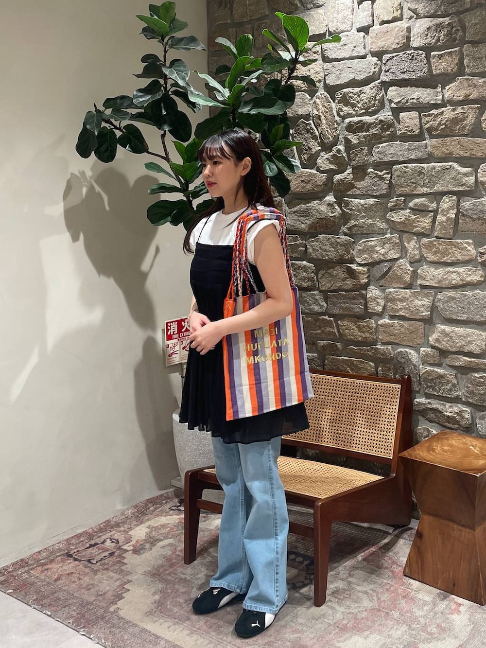 ブラック系のスニーカー、ブルー系のデニムパンツ、パープル系のトートバッグを着用したレディースの春コーディネートの2枚目の写真