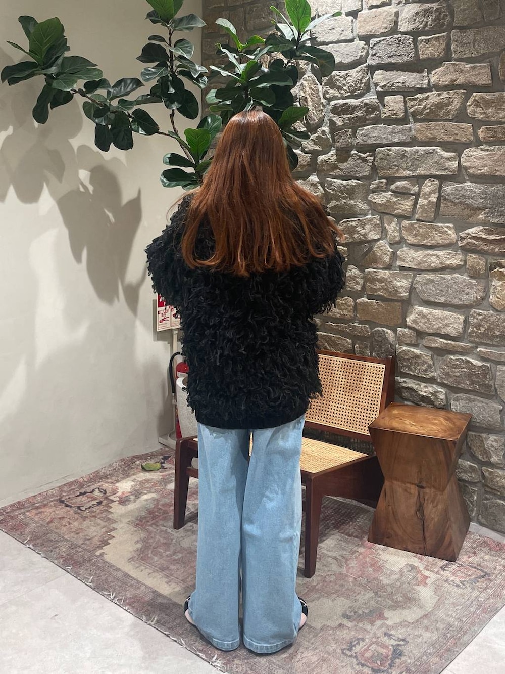 ホワイト系のハンドバッグ、ブルー系のデニムパンツ、ブラック系のカーディガン/ボレロを着用したレディースの冬コーディネートの3枚目の写真