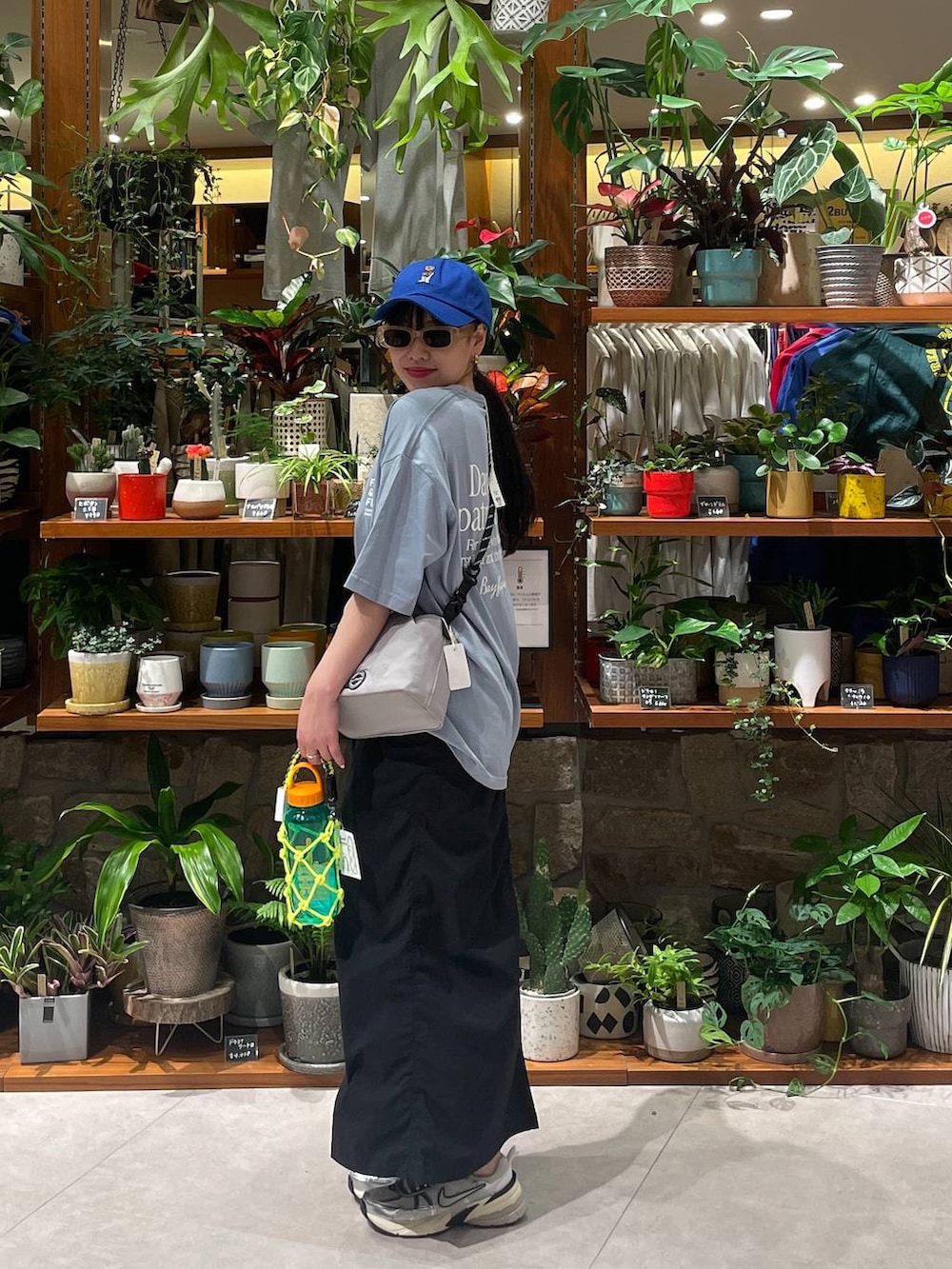 ブラック系のスカート、グレー系のショルダーバッグ、グリーン系の水筒を着用したレディースの春コーディネートの2枚目の写真